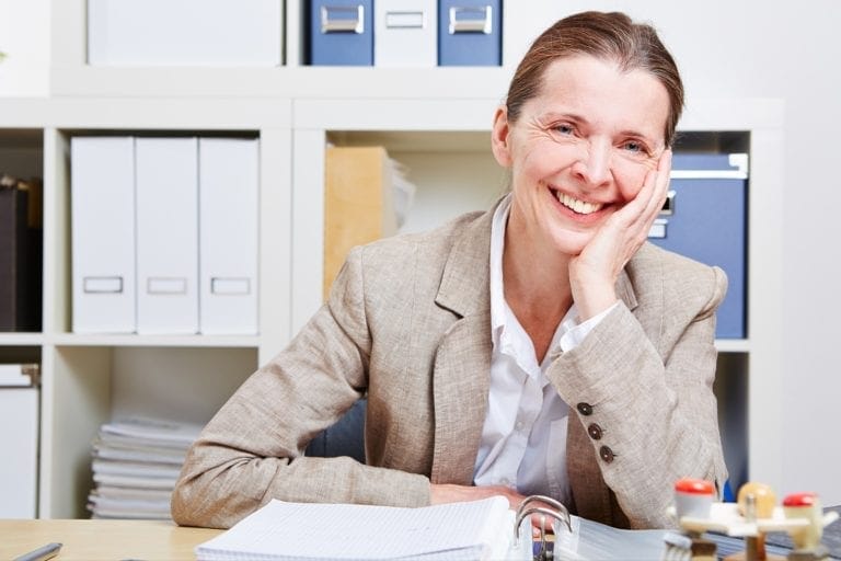 Portrait of a happy elderly woman in her office at the desk