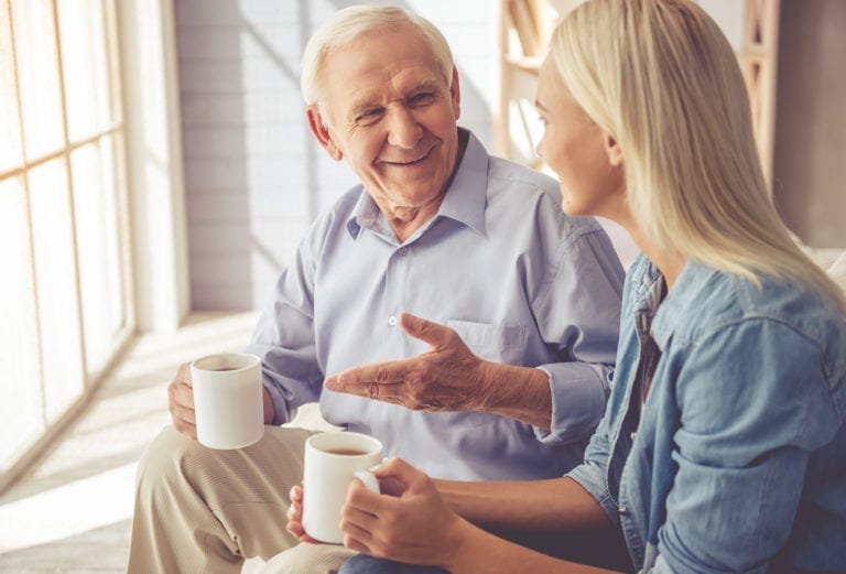 a dementia caregiver and her father enjoy conversation over coffee