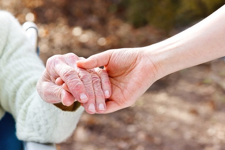 Caregiver holding a senior woman's hand