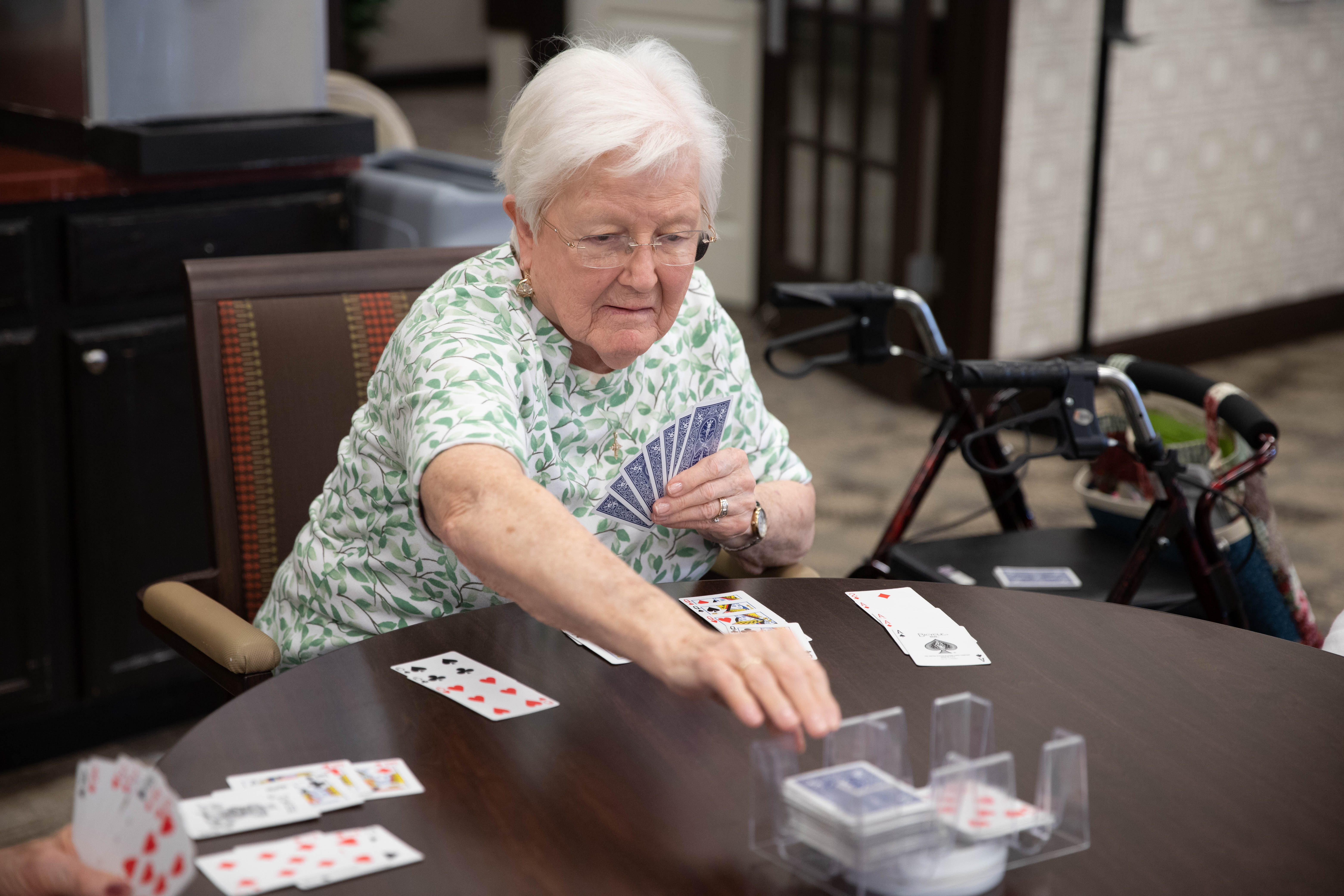 <span  class="uc_style_uc_tiles_grid_image_elementor_uc_items_attribute_title" style="color:#000000;">A resident is playing cards at a table. </span>