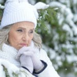 Senior woman outside in front of trees in a snowy background