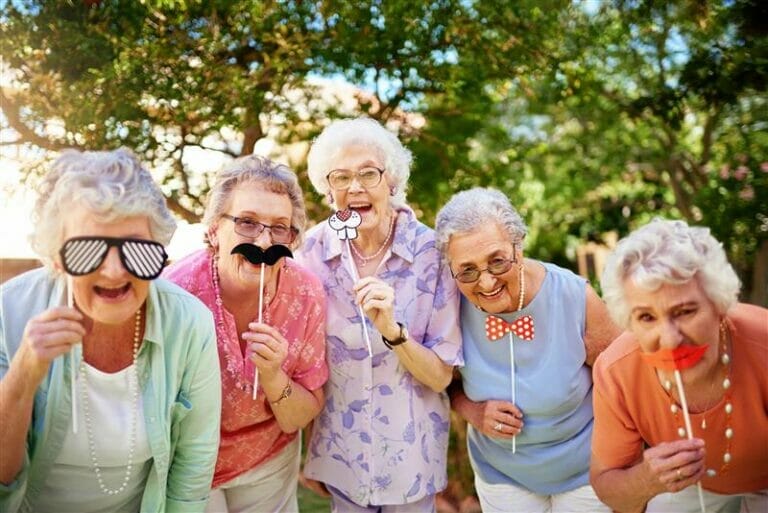 Group of senior women laughing playing with costume props.