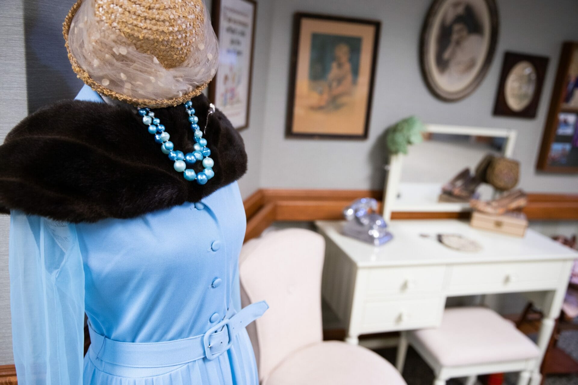 <span  class="uc_style_uc_tiles_grid_image_elementor_uc_items_attribute_title" style="color:#000000;">A blue dress on a mannequin in a vintage-style room with black and white pictures and an antique white vanity.</span>