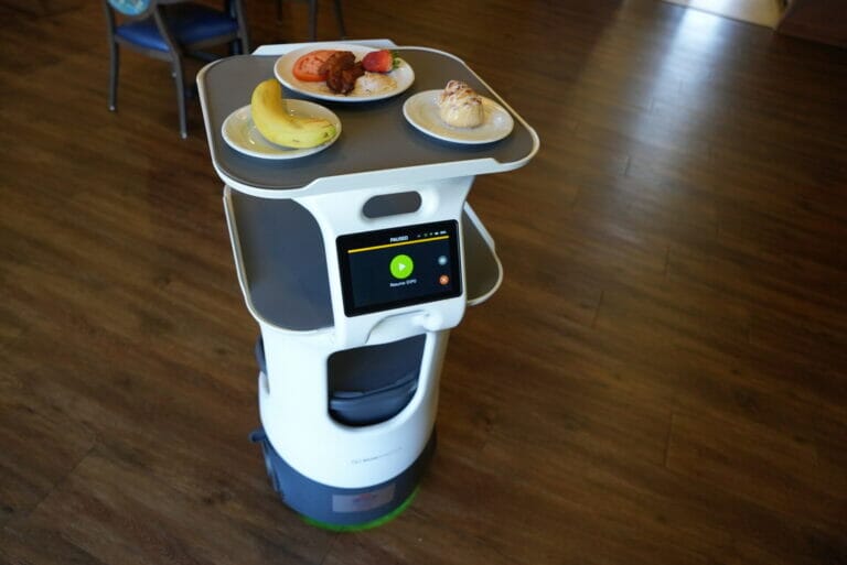 Robot server with plates of food on top.