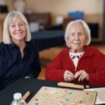 Centenarian Cecil Butler wearing red sweater while playing scrabble with her daughter