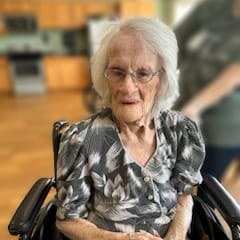 Centenarian Mary Hurt wearing a black and white floral dress and sitting in a wheelchair